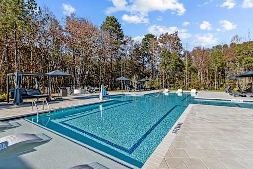A large swimming pool surrounded by trees and a wooden deck.