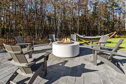 A fire pit surrounded by chairs on a patio.