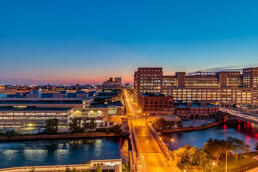 A cityscape at dusk with buildings and a river.