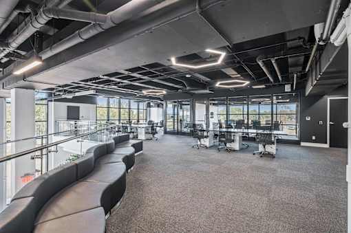 A modern office space with black leather seating and large windows.