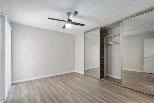 A room with a ceiling fan and sliding glass doors.