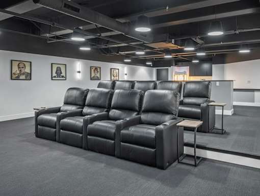 A row of black leather reclining chairs are lined up in a room.