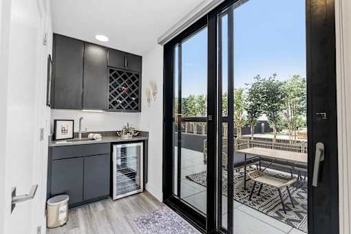 A modern kitchen with a view of the backyard through the glass doors.