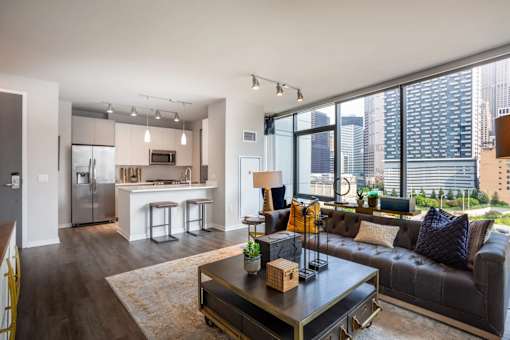 A modern living room with a black leather couch and a coffee table in the center.