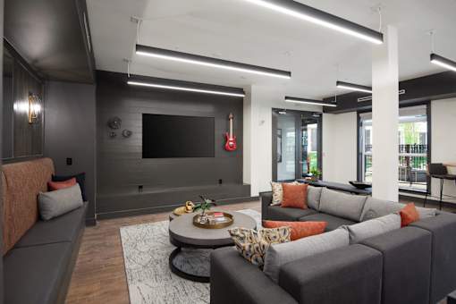 A modern living room with a grey couch and a flat screen TV mounted on the wall.