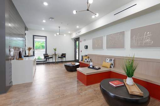 A modern office space with a black leather ottoman and a white table with a red book on it.
