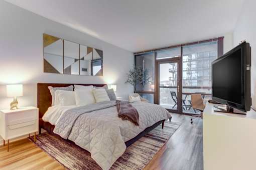 A bedroom with a large bed, a television, and a chair.