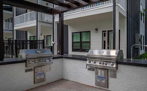 A stainless steel grill is attached to a brick wall.