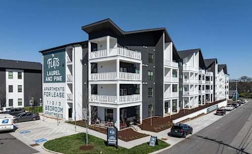 A building with a sign that says "Flats Laurel and Pine Apartments for lease 1/1/3 bedroom apartments".