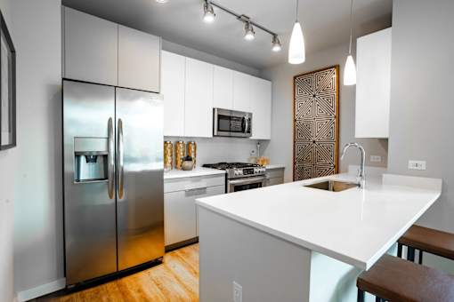 A modern kitchen with a white countertop and stainless steel appliances.