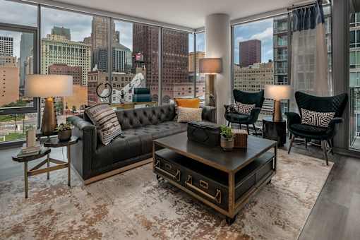 A black leather couch sits in a living room with a city view.