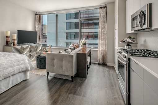 A modern living room with a large bed and a kitchen area.