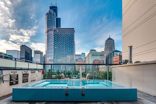 A swimming pool on a rooftop with a city skyline in the background.