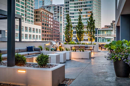 A rooftop patio with a couch, chairs, and potted plants.