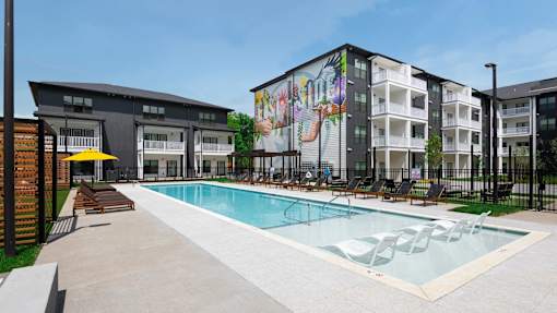 A pool in front of a building with a mural on the side.