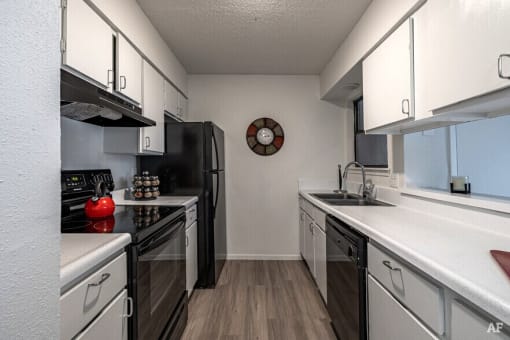 a kitchen with white cabinets and black appliances