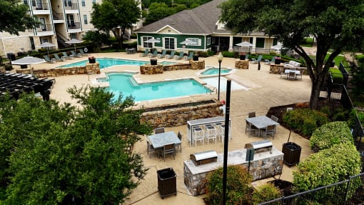 an aerial view of a pool and patio with tables and umbrellas