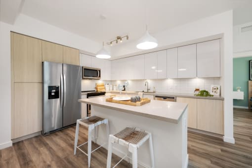 a kitchen with a large island and a stainless steel refrigerator