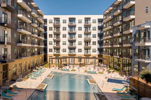 A large swimming pool in the middle of a courtyard surrounded by apartment buildings.
