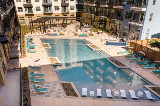 A large swimming pool surrounded by lounge chairs and umbrellas.