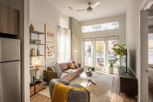 A modern living room with a grey sofa, a yellow throw blanket, and a ceiling fan.