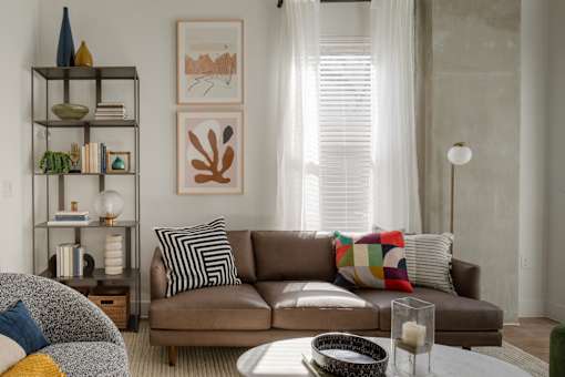 A living room with a brown couch and a glass table.