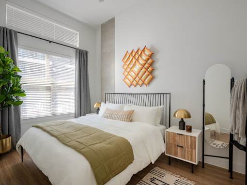 A bedroom with a white bed and a green quilt.