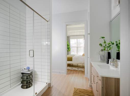 A bathroom with a white tiled shower and a wooden floor.