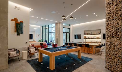 A room with a pool table and a stone pillar.