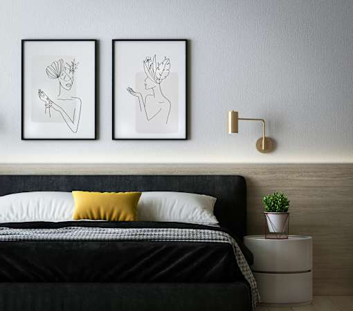 A bedroom with a black bed and two framed artworks on the wall.