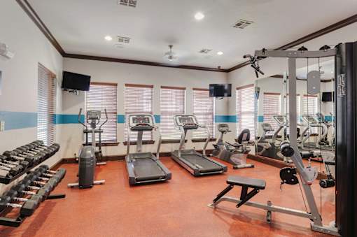 A gym with a variety of equipment including treadmills, weights, and exercise machines.