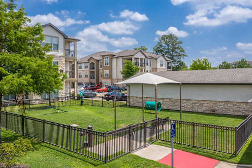 A sunny day at a residential complex with a playground and a red mat.