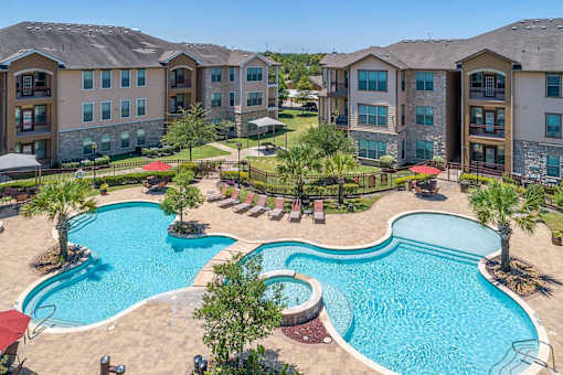 A large swimming pool surrounded by palm trees and lounge chairs.