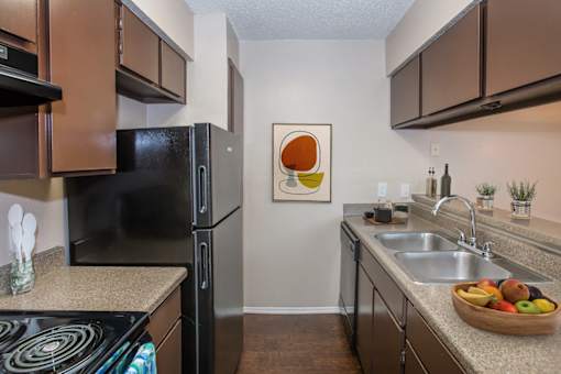 A kitchen with brown cabinets and a black refrigerator.