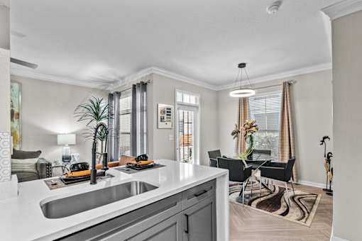 A modern kitchen with a dining area in the background.