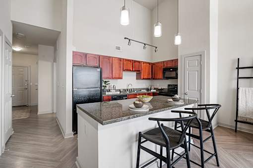 A kitchen with a black refrigerator and wooden cabinets.
