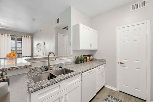 A kitchen with white cabinets and a granite countertop.