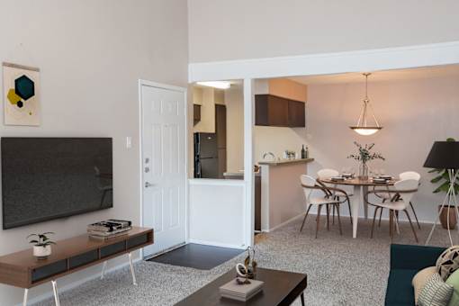 A living room with a television, a dining table, and chairs.