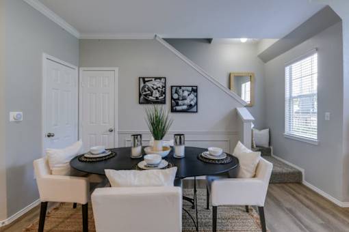 A dining room with a black table and white chairs.