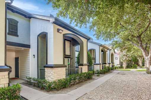 A row of houses with a sidewalk and trees.