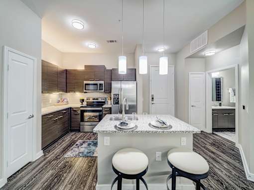 A kitchen with a white island and bar stools.