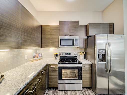 A modern kitchen with a stainless steel refrigerator and oven.