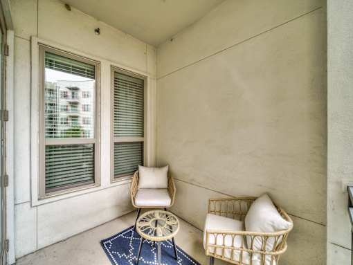 A chair and a basket with pillows are on a balcony.