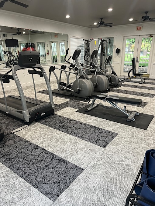 A gym with treadmills, exercise bikes, and weights.