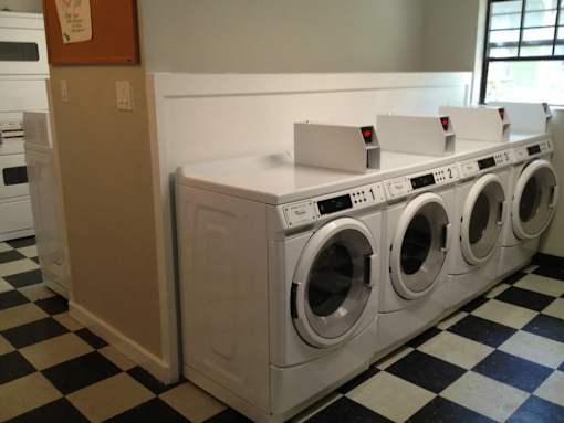 A row of white front load washing machines in a laundromat.