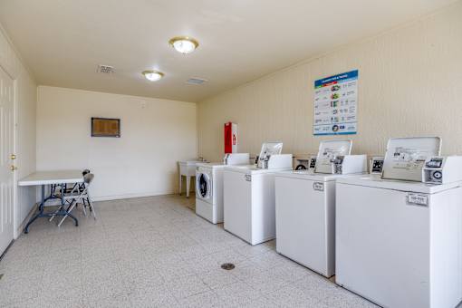 A laundry room with washers and dryers and a table.