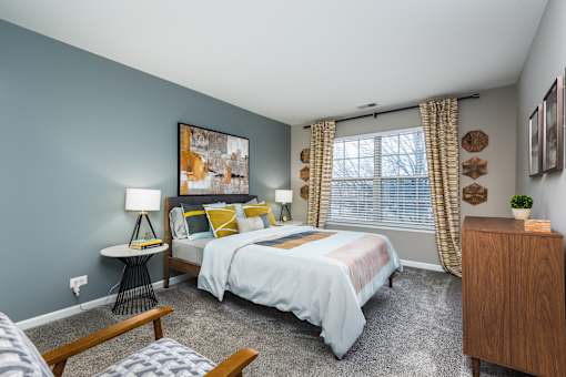 A bedroom with a bed, nightstand, and a painting on the wall.