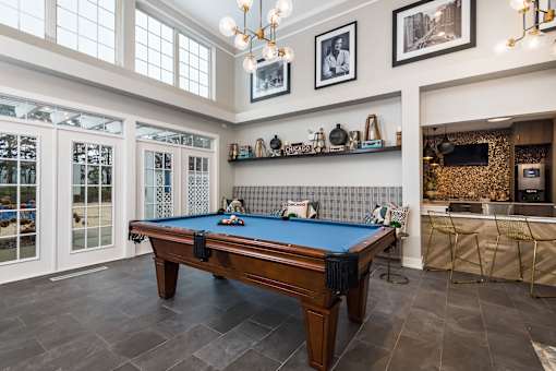 A pool table in a room with a television and a bar area.