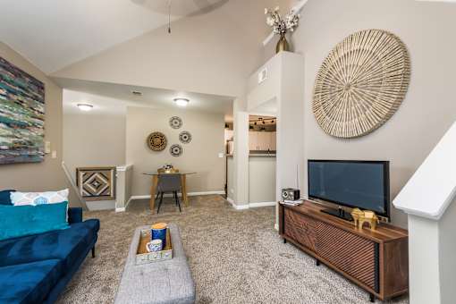 A living room with a blue couch and a wooden entertainment center.