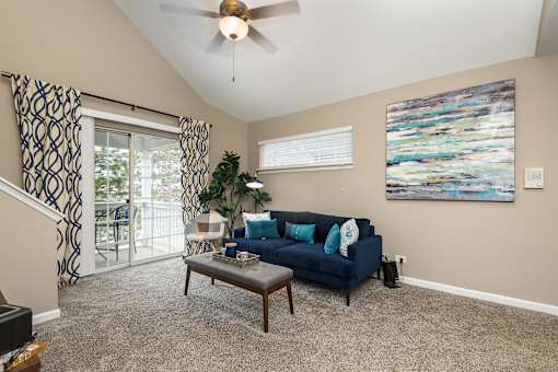 A living room with a blue couch and a painting on the wall.